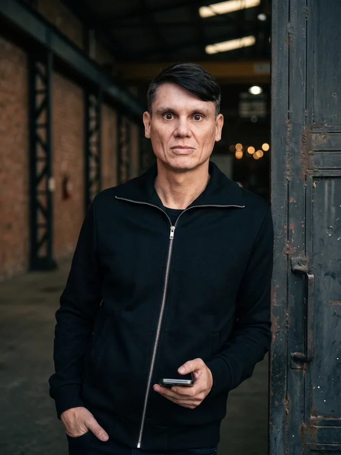 Aldo Batista em ambiente industrial, com o celular na mão