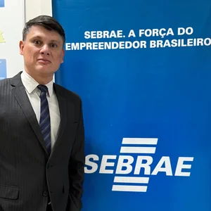 Aldo Batista ao lado de banner do SEBRAE